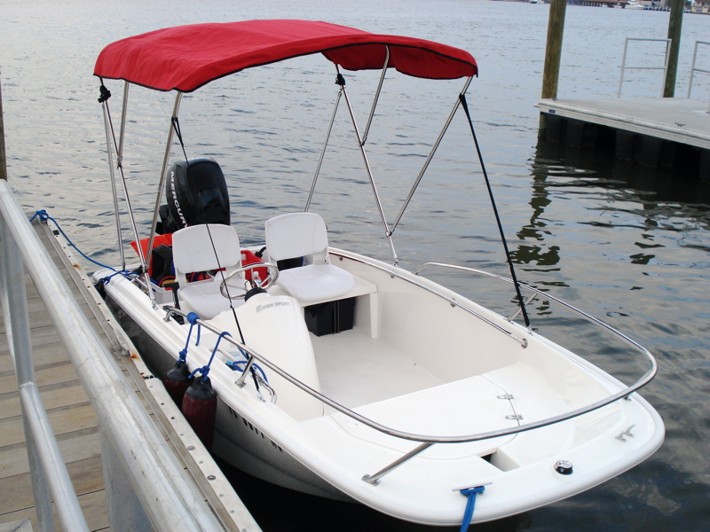 A boat with a bimini top docked at a jetty