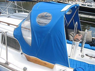 A boat with a blue boat canopy docked at a jetty