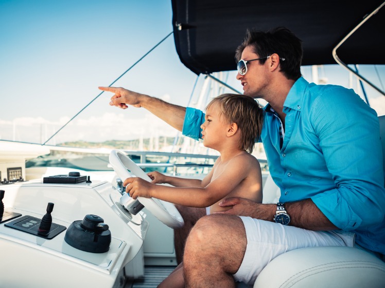 A father and son spending time on their boat, sitting under the bimini top