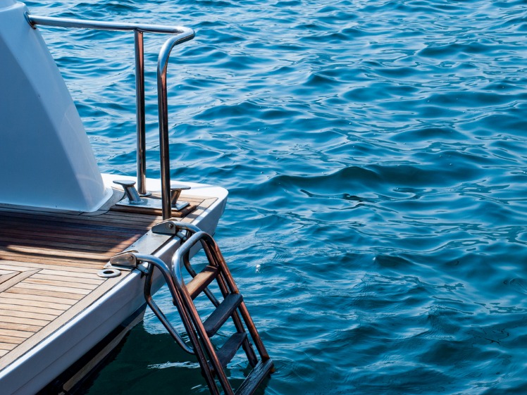 a boat ladder at the back of a boat going into the sea