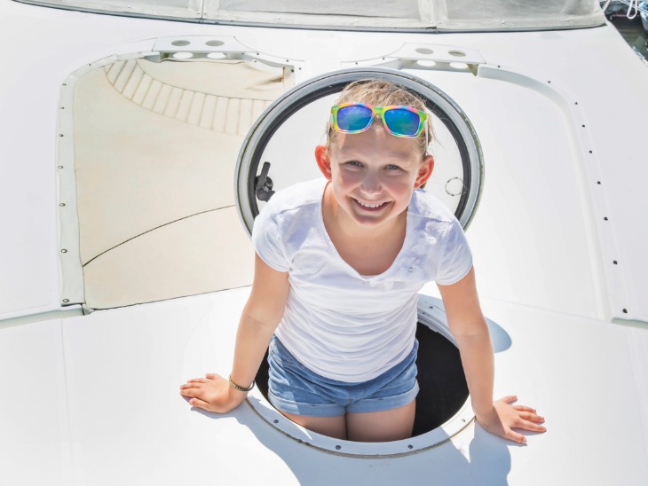 a young girl comes out of the deck hatch on a boat