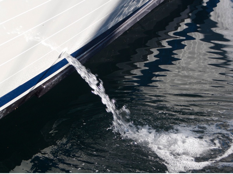 A bilge pump working properly - water coming out of the hull of a yacht