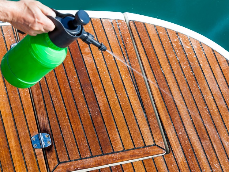 Spray gun cleaning wooden deck on a boat