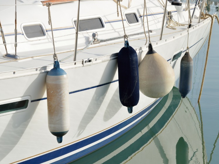 four different sized buoy fenders on the side of a white boat in the water