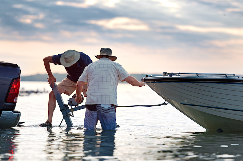 Two men using a trailer winch to pull their boat up onto the boat trailer